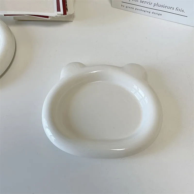 White ceramic plate with cartoon bear doodle design, shown next to round toot design plate, both microwave safe.