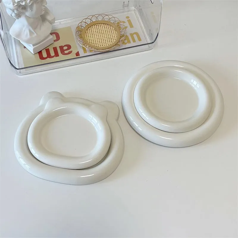 White ceramic plate with cartoon bear doodle design, shown next to round toot design plate, both microwave safe.