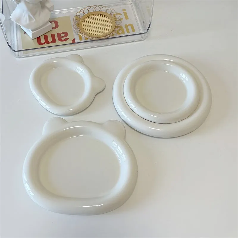 White ceramic plate with cartoon bear doodle design, shown next to round toot design plate, both microwave safe.
