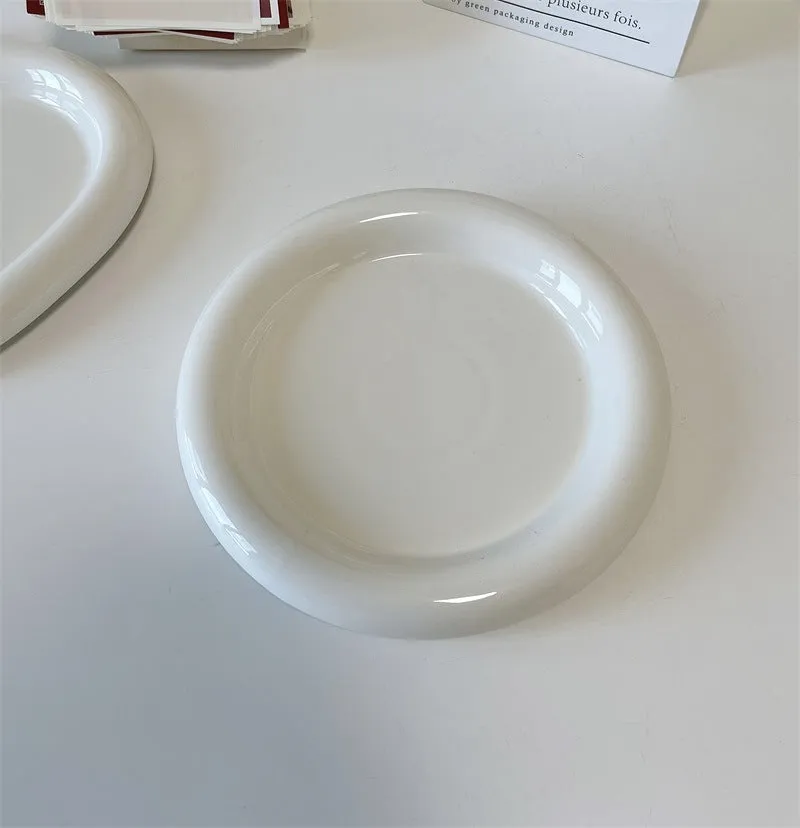 White ceramic plate with cartoon bear doodle design, shown next to round toot design plate, both microwave safe.