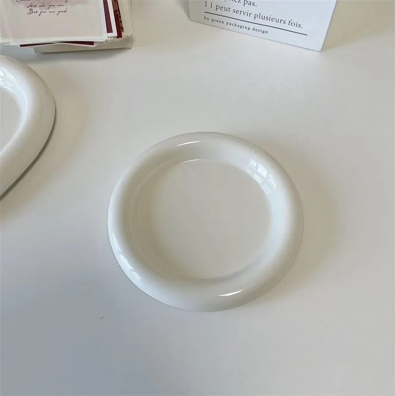 White ceramic plate with cartoon bear doodle design, shown next to round toot design plate, both microwave safe.