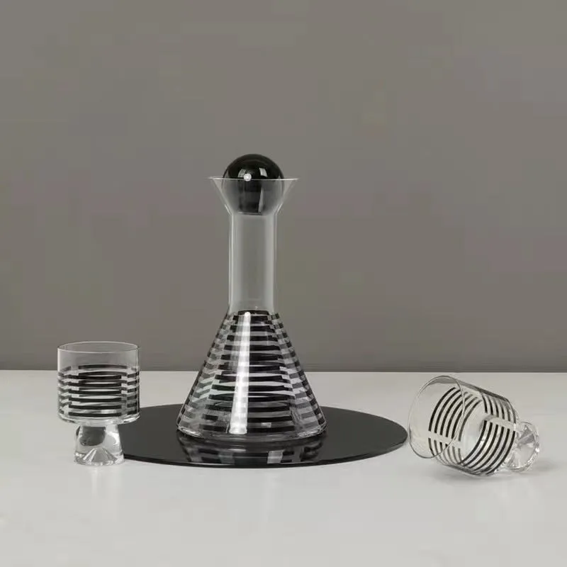 Modern black striped glass cold water bottle 1000ml with two cups on a light surface