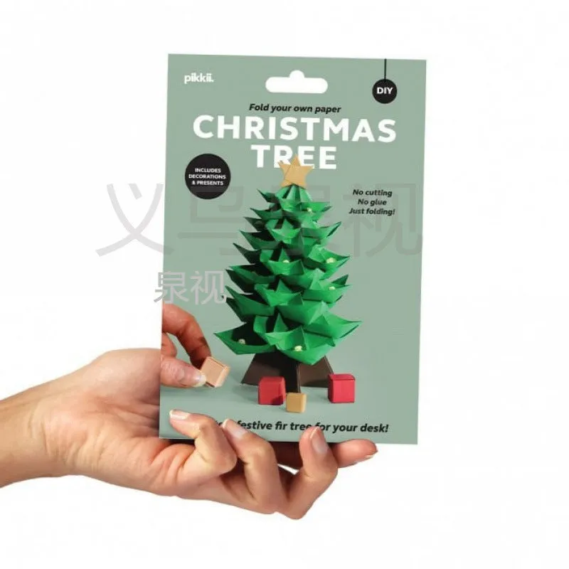 Christmas tree paper folding kit with origami sheets, small scissors, and instruction manual on a desktop