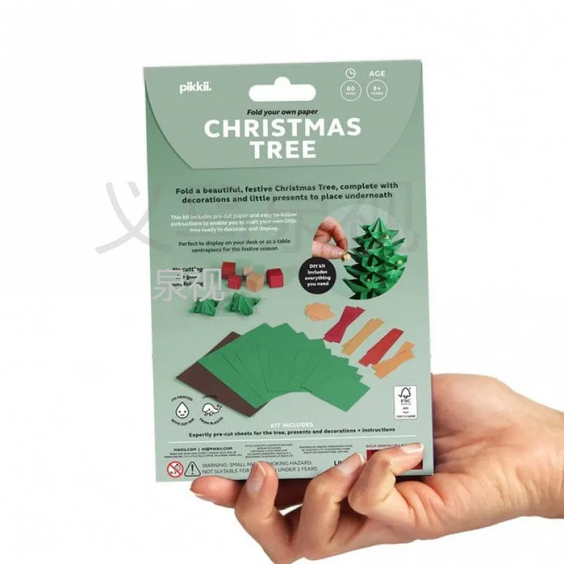 Christmas tree paper folding kit with origami sheets, small scissors, and instruction manual on a desktop