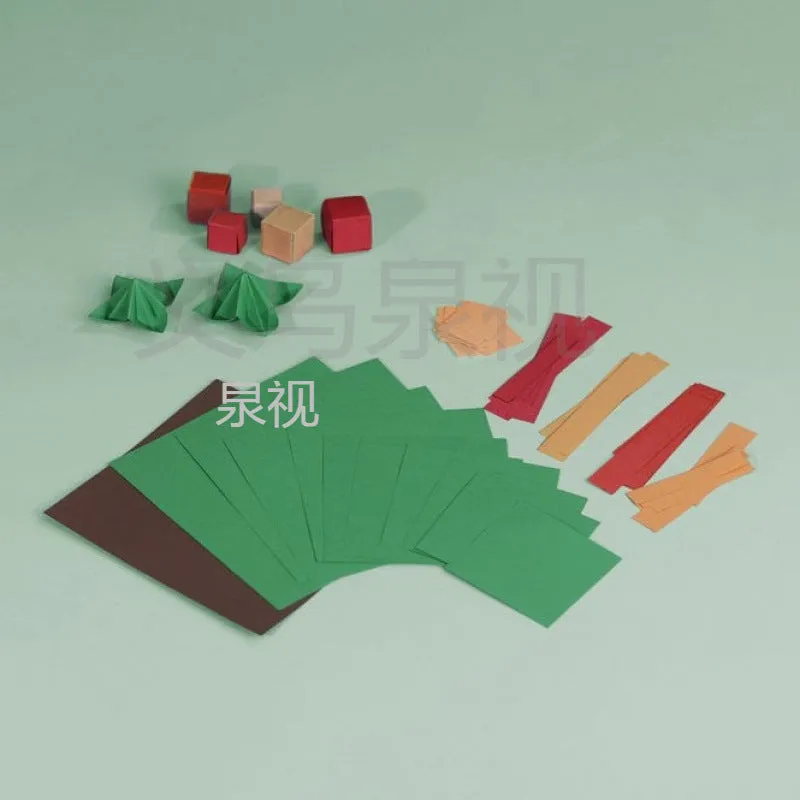 Christmas tree paper folding kit with origami sheets, small scissors, and instruction manual on a desktop