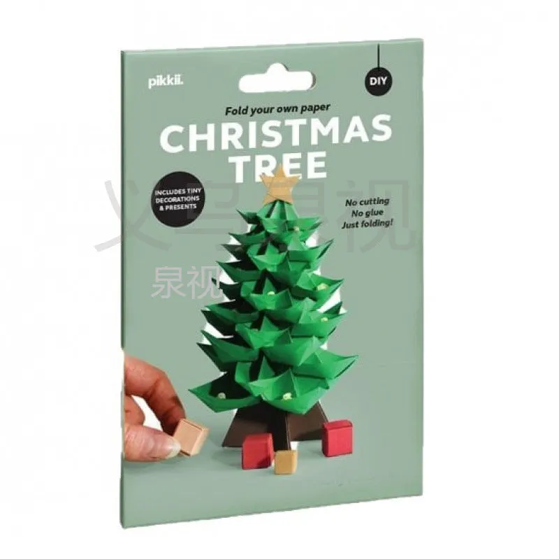 Christmas tree paper folding kit with origami sheets, small scissors, and instruction manual on a desktop