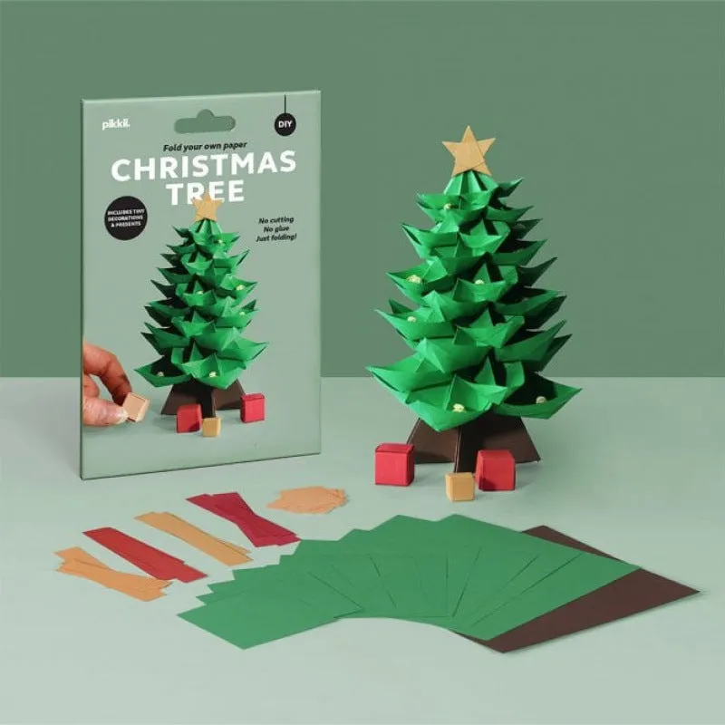 Christmas tree paper folding kit with origami sheets, small scissors, and instruction manual on a desktop