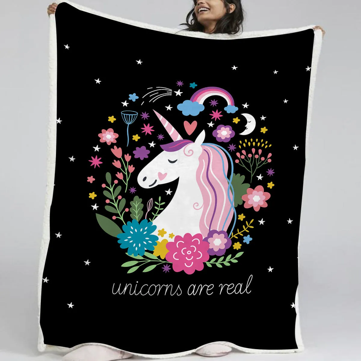 Black sherpa fleece blanket folded on a couch, soft fabric with hemmed edges.
