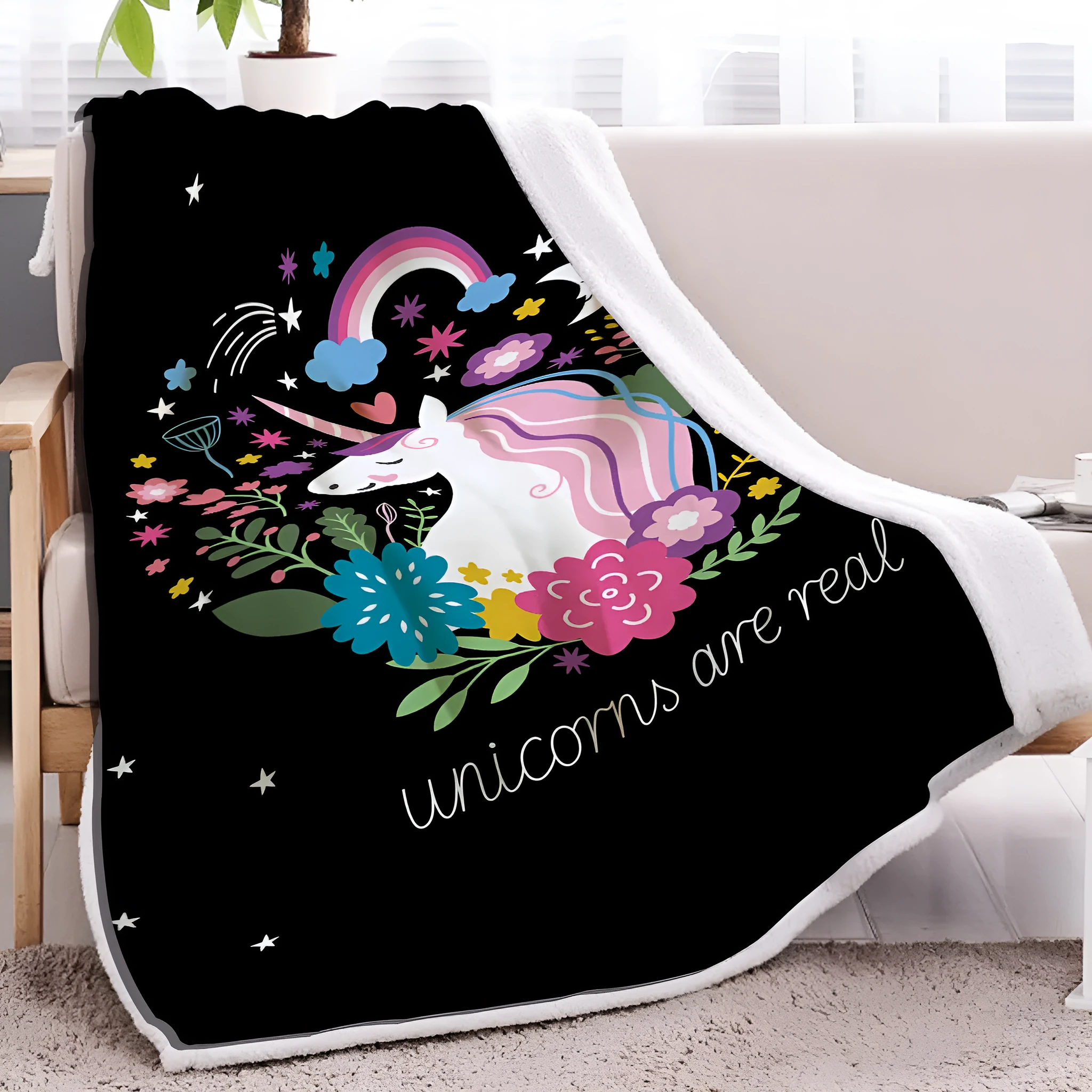 Black sherpa fleece blanket folded on a couch, soft fabric with hemmed edges.