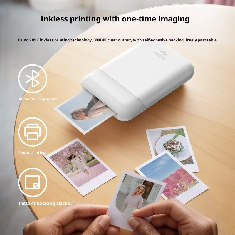 Pocket photo printer in plastic casing with carry-on bag and photo paper on table