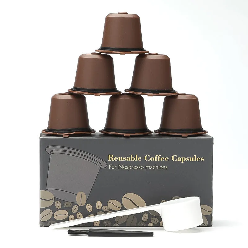 Six reusable black plastic coffee capsule filter cups with a spoon on a table