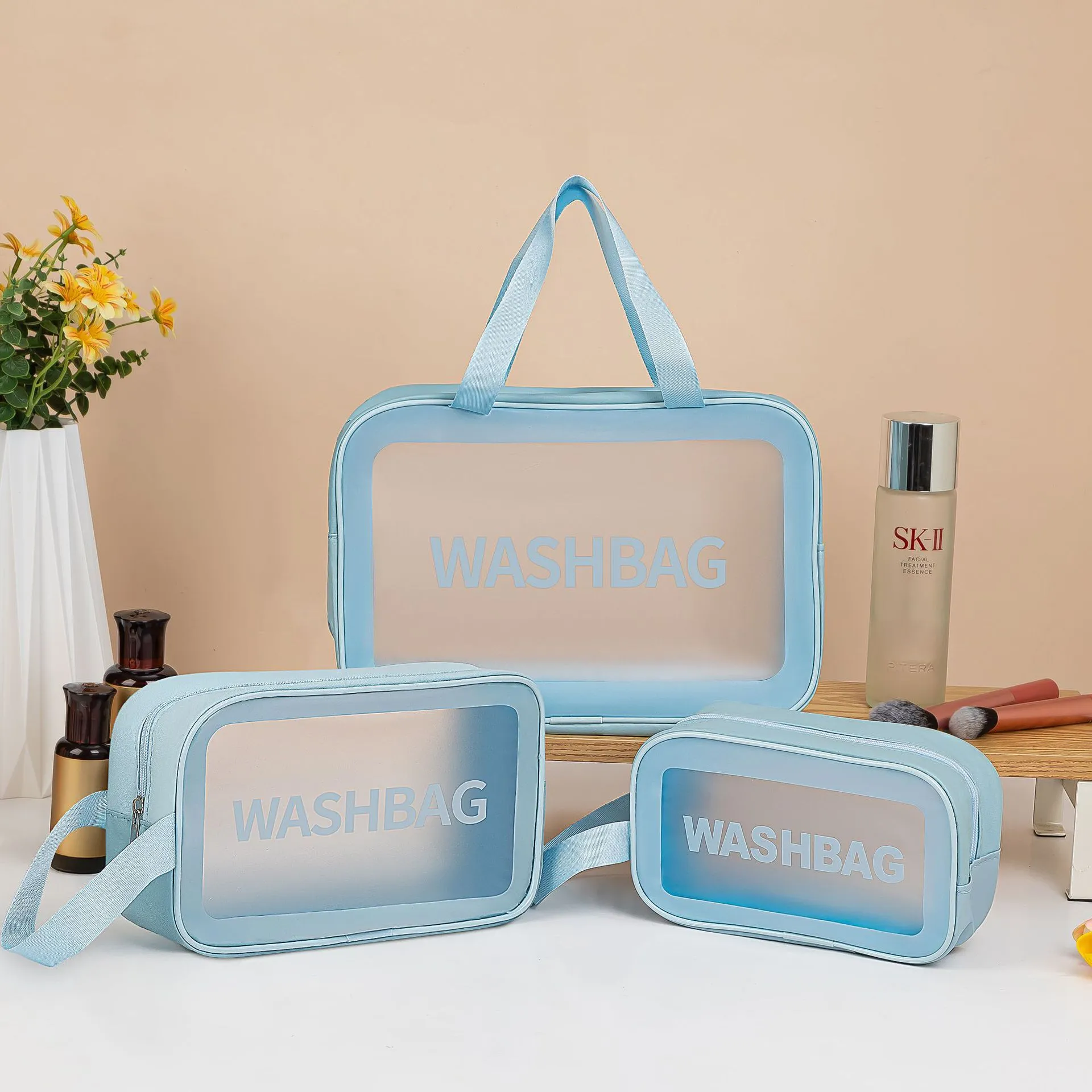 Large PVC transparent cosmetic bag three-piece set in various colours including beige, black, blue, pink, and white, empty and open on a flat surface