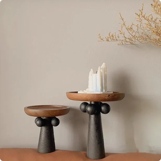 Nordic style round wooden tray with high legs for displaying candles and aromatherapy items.