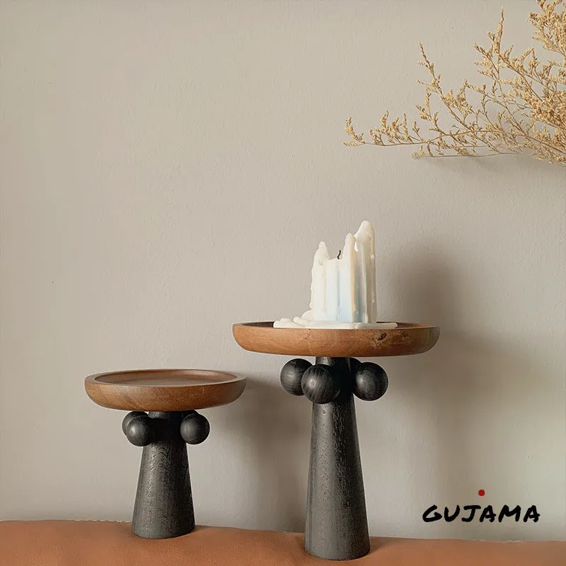 Nordic style round wooden tray with high legs for displaying candles and aromatherapy items.