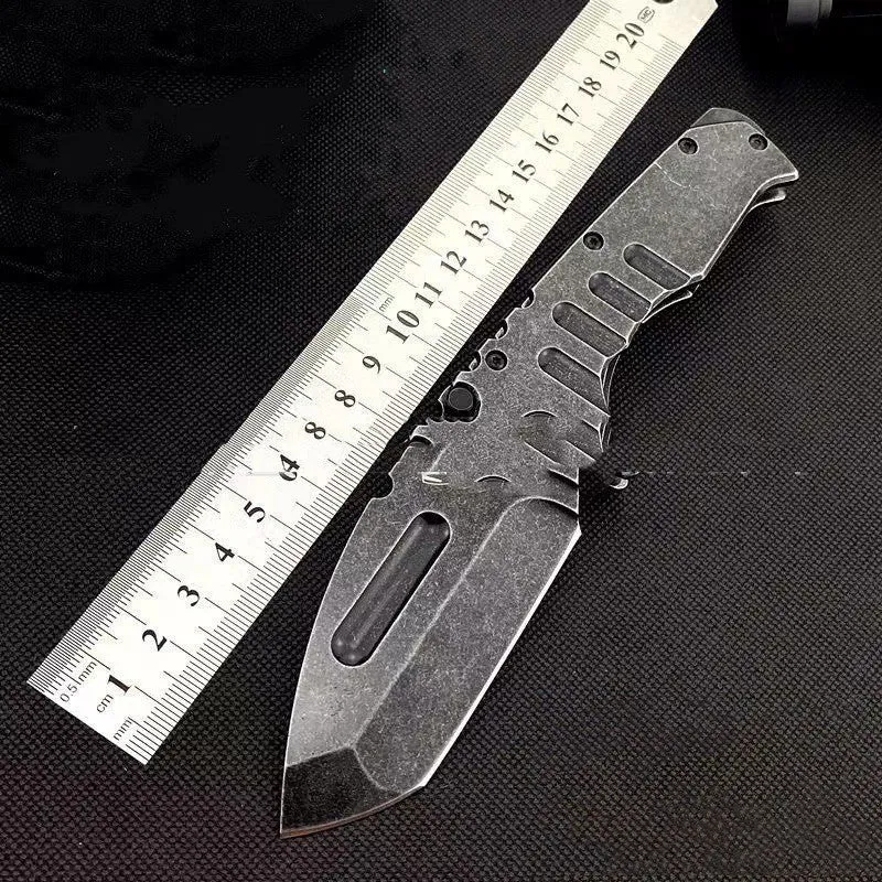 907 style outdoor folding knife with D2 steel blade, 9 cm blade, black handle, closed position on grey background