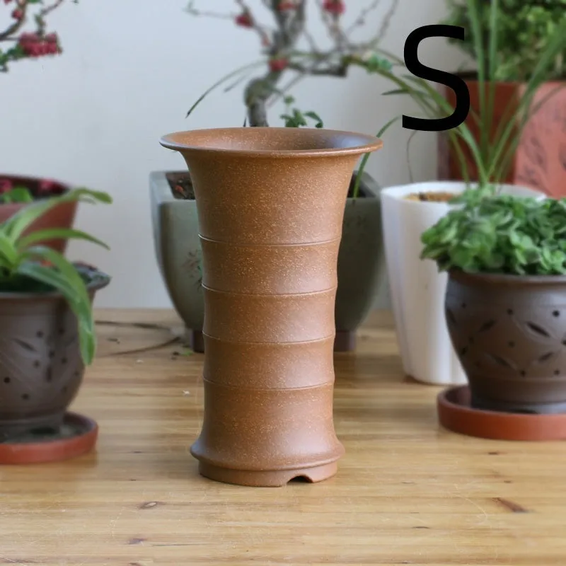 Boutique handmade descending slope ceramic orchid pot in mud purple sand on desktop