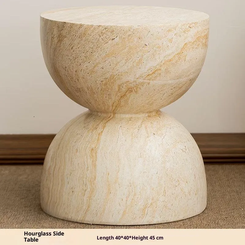 Modern hourglass-shaped tea table in imitation cave stone finish placed beside a sofa in a living room