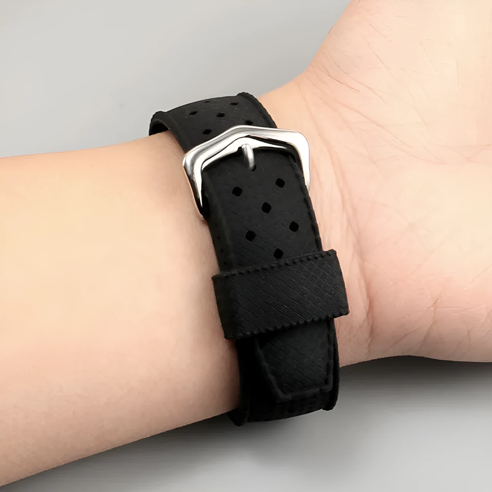 Black silicone watch strap with silver pin buckle and raised mouth design for blue dial watches
