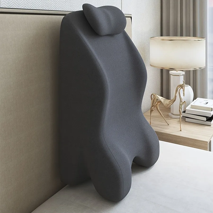 A prone position stomach sleeping pillow shown in a light grey colour, designed for use while reading in bed.