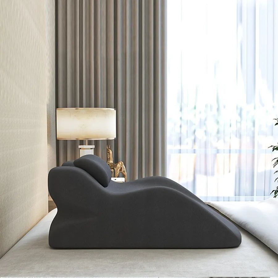 A prone position stomach sleeping pillow shown in a light grey colour, designed for use while reading in bed.