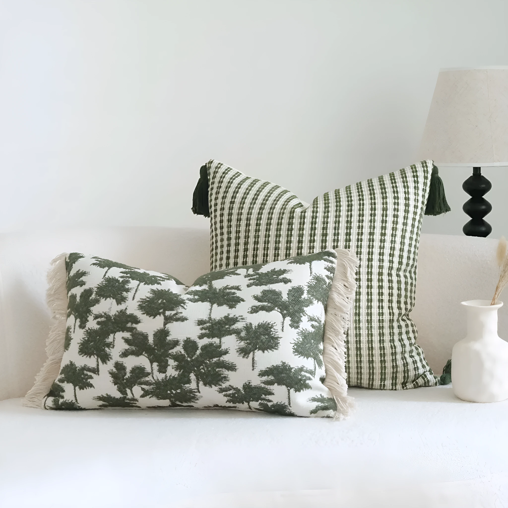 Green cotton and linen hotel sample pillow with botanical pattern and tassel detail on a display bed.