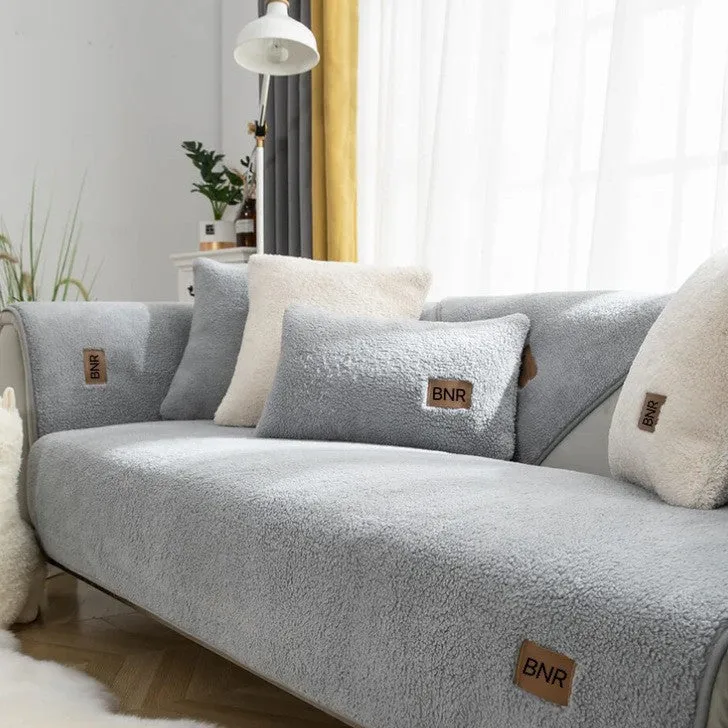 Solid colour lambswool sofa cover draped over a sofa, showing simple style and cloth liner.