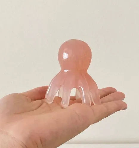 Pink octopus-shaped massage comb for periocular meridian acupressure with curved arms and storage bag