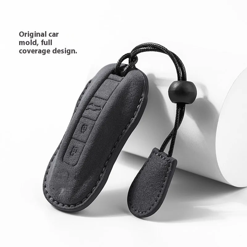 Suede car key cover in cement grey, dark green, light grey, and orange colour options on a plain background.