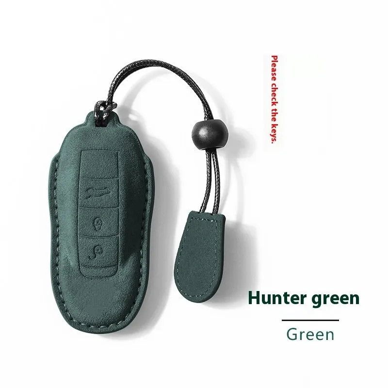 Suede car key cover in cement grey, dark green, light grey, and orange colour options on a plain background.
