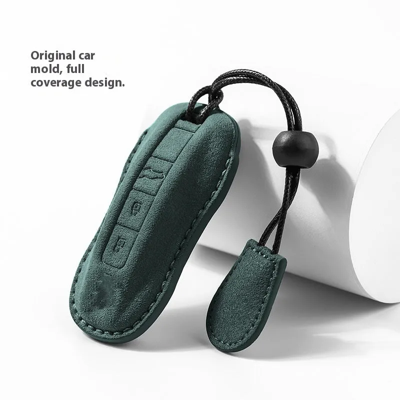 Suede car key cover in cement grey, dark green, light grey, and orange colour options on a plain background.