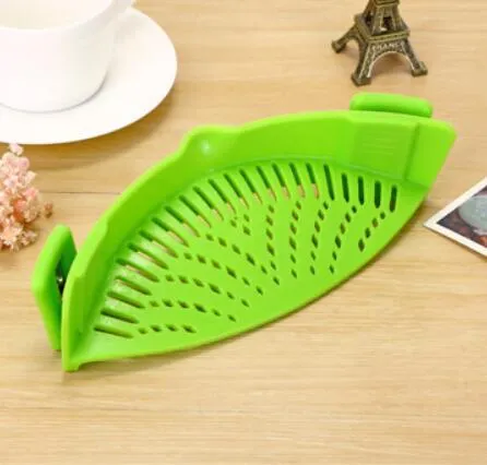 Silicone clip-on kitchen strainer with stainless steel frame attached to pot rim for draining liquids