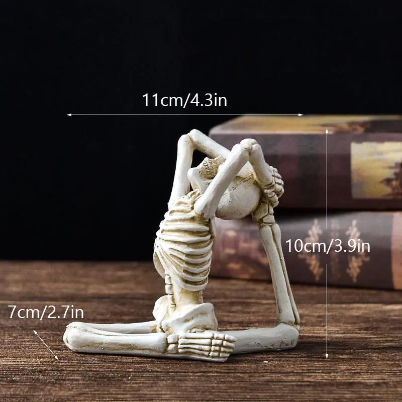Hand-painted resin yoga pose skull skeleton ornament measuring 10.5-11cm wide on wooden desktop