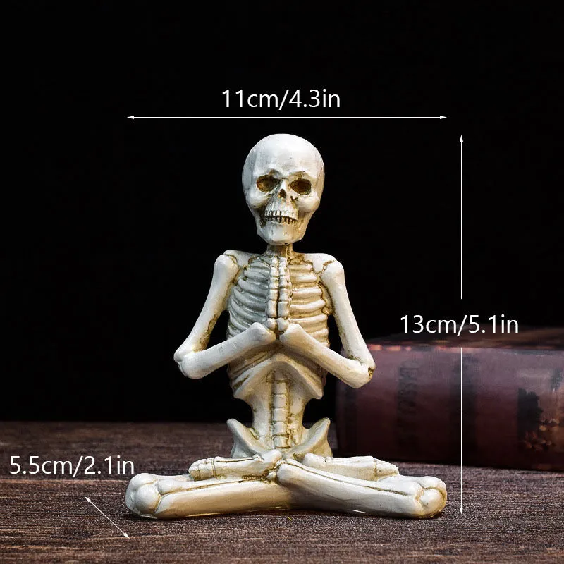 Hand-painted resin yoga pose skull skeleton ornament measuring 10.5-11cm wide on wooden desktop