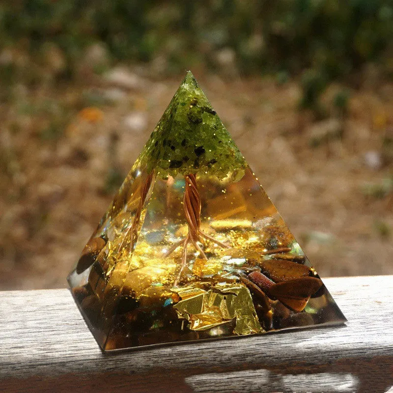 Small 6cm high clear epoxy resin pyramid ornament filled with colourful natural crystal gravel on a shelf.