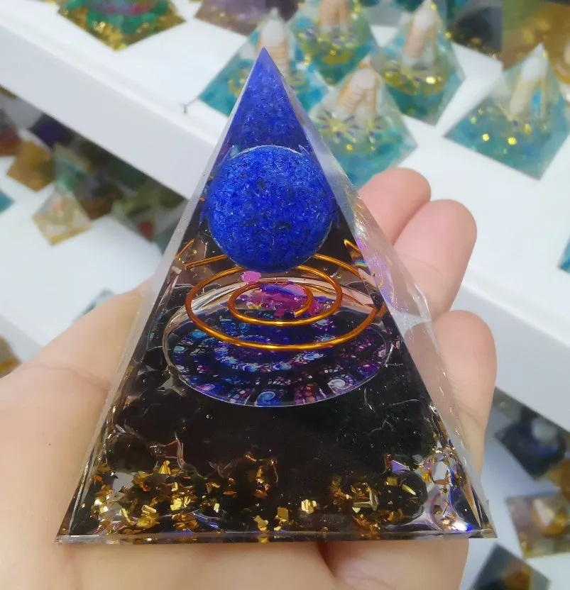 Small 6cm high clear epoxy resin pyramid ornament filled with colourful natural crystal gravel on a shelf.