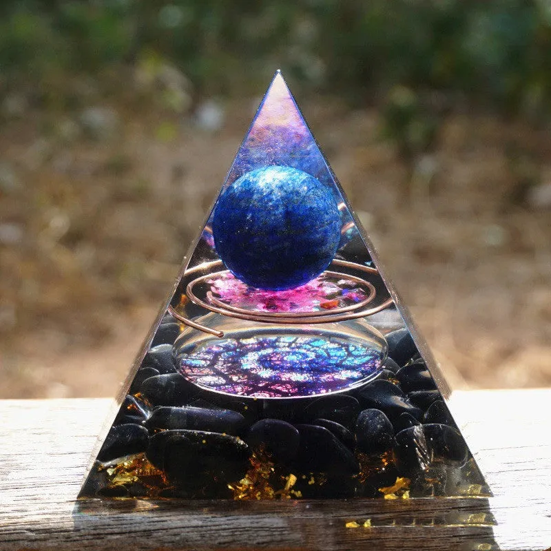 Small 6cm high clear epoxy resin pyramid ornament filled with colourful natural crystal gravel on a shelf.
