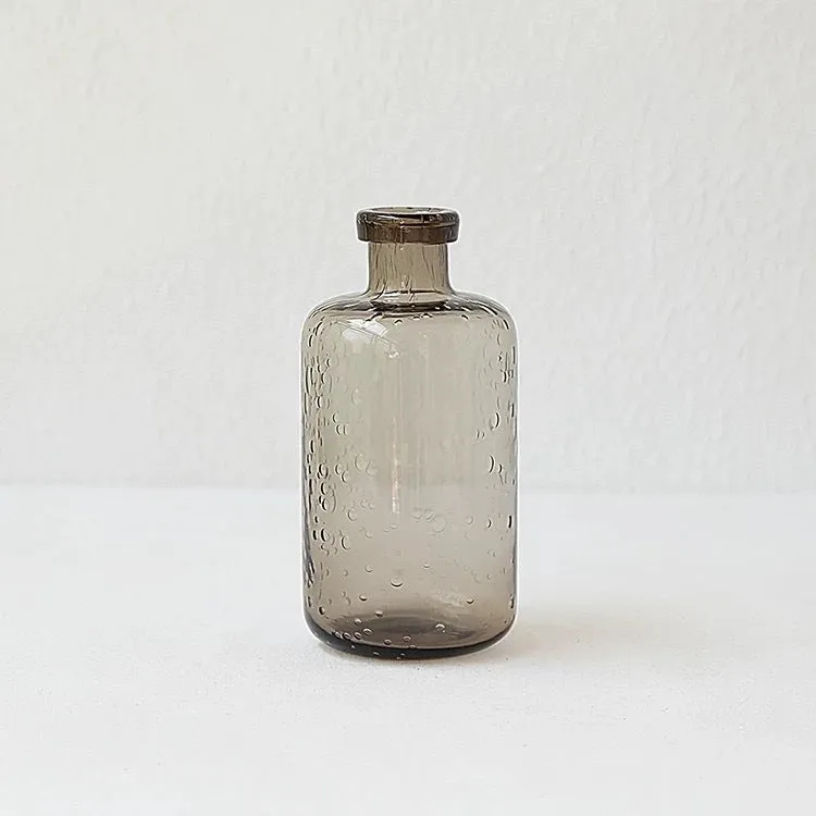 Grey geometric bubble-shaped stained glass vase on a wooden surface.