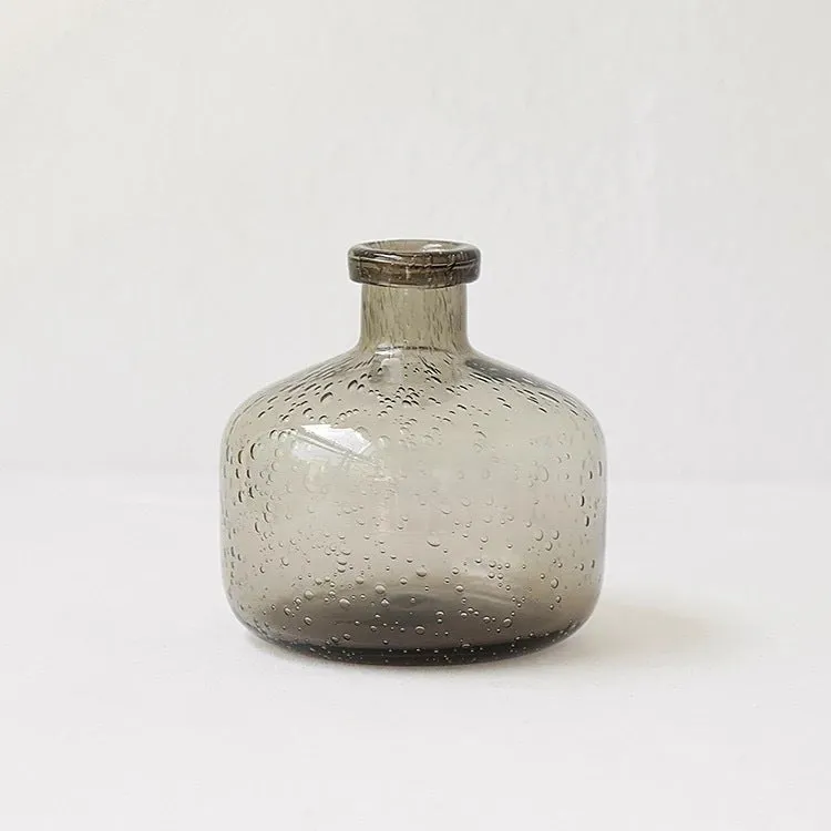 Grey geometric bubble-shaped stained glass vase on a wooden surface.