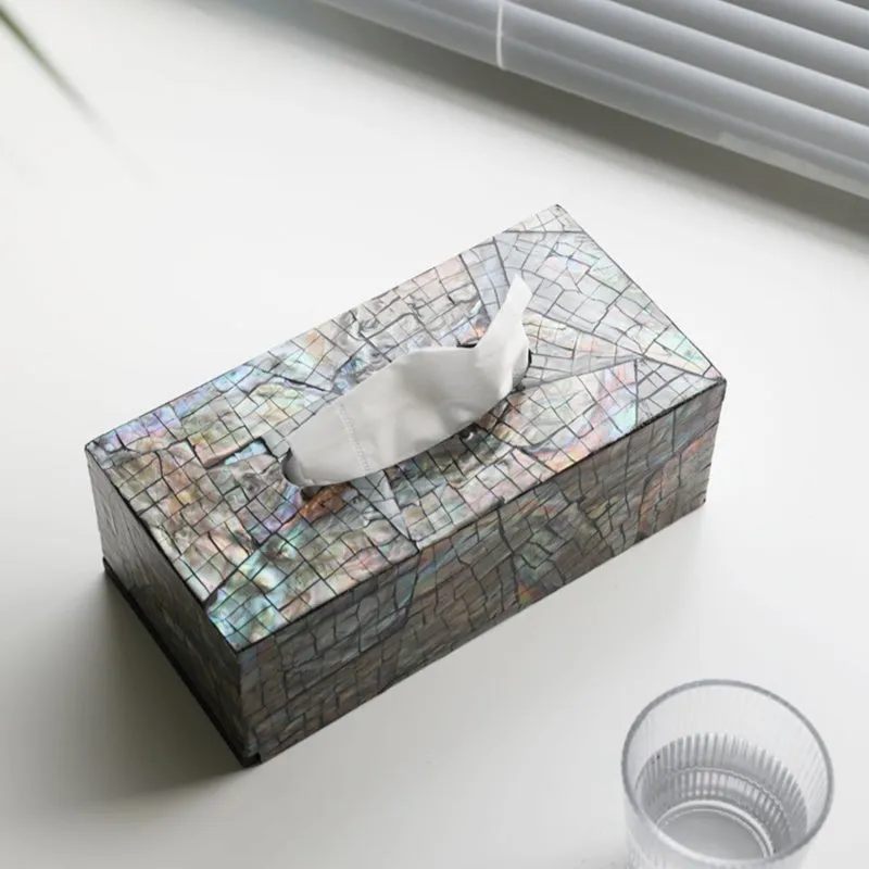 A black square natural shell storage box with a removable white internal organiser on a wooden table.