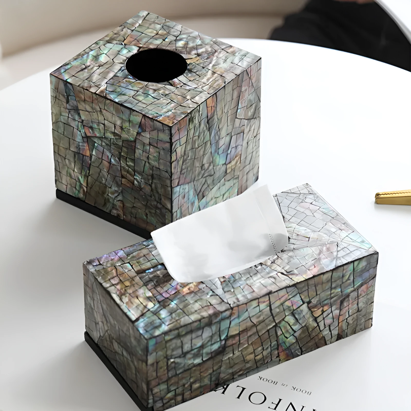 A black square natural shell storage box with a removable white internal organiser on a wooden table.
