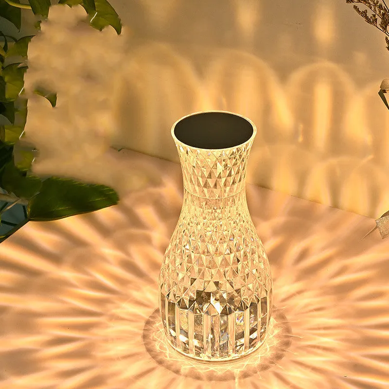 Vase-shaped transparent crystal bedside lamp with touch controls and LED lights on a table.