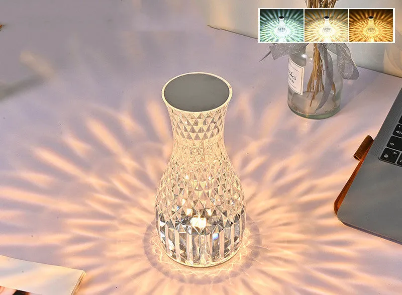 Vase-shaped transparent crystal bedside lamp with touch controls and LED lights on a table.