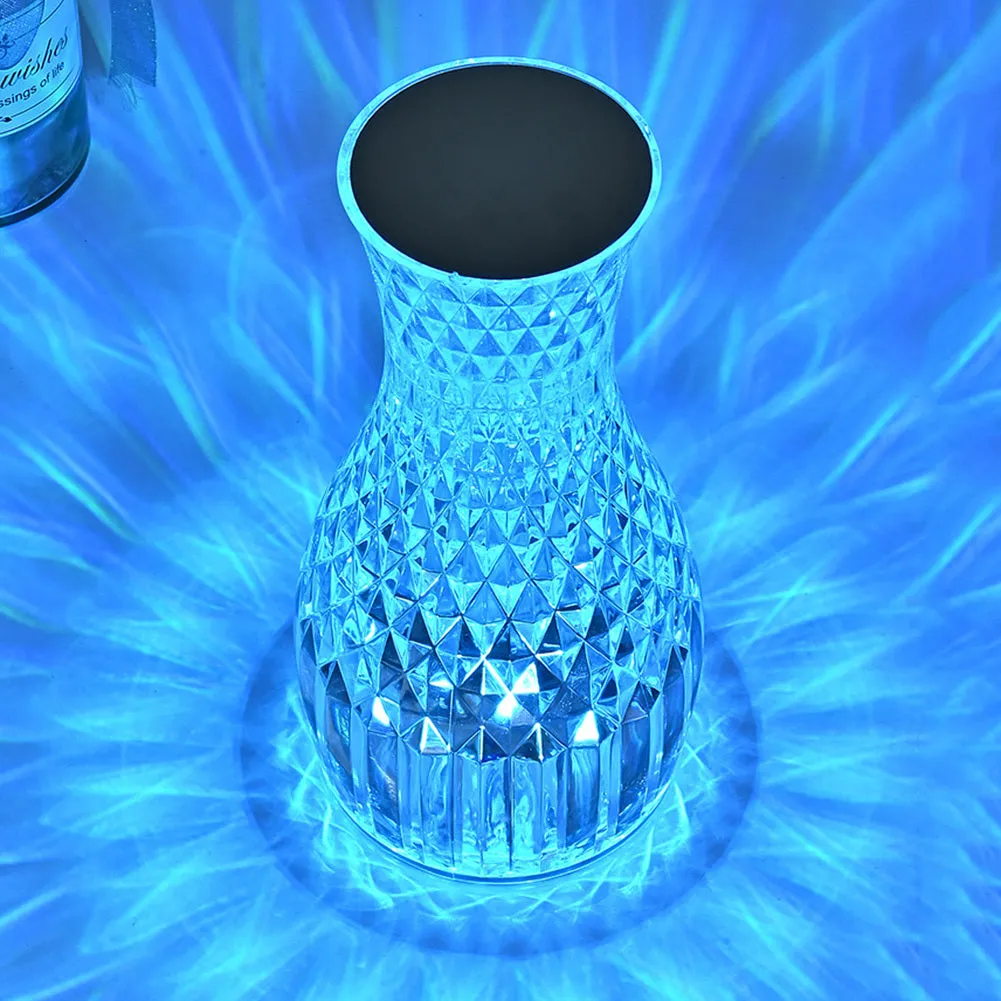 Vase-shaped transparent crystal bedside lamp with touch controls and LED lights on a table.