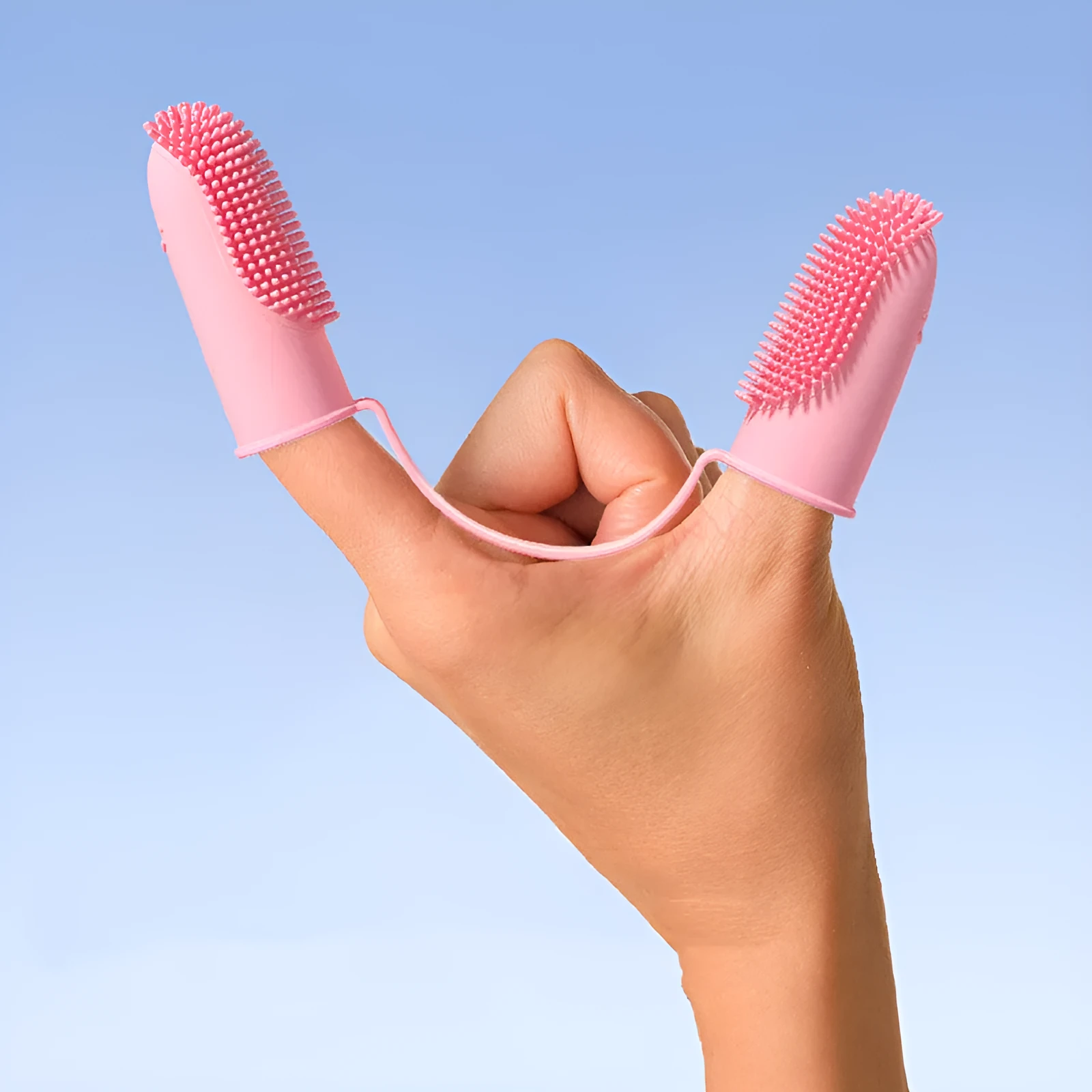 Close-up of blue green and pink silicone finger sleeves for pet dental cleaning on a hand.