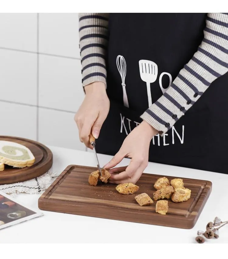 Solid black walnut wood chopping board with a deep perimeter groove and a side handle, shown as a serving tray.
