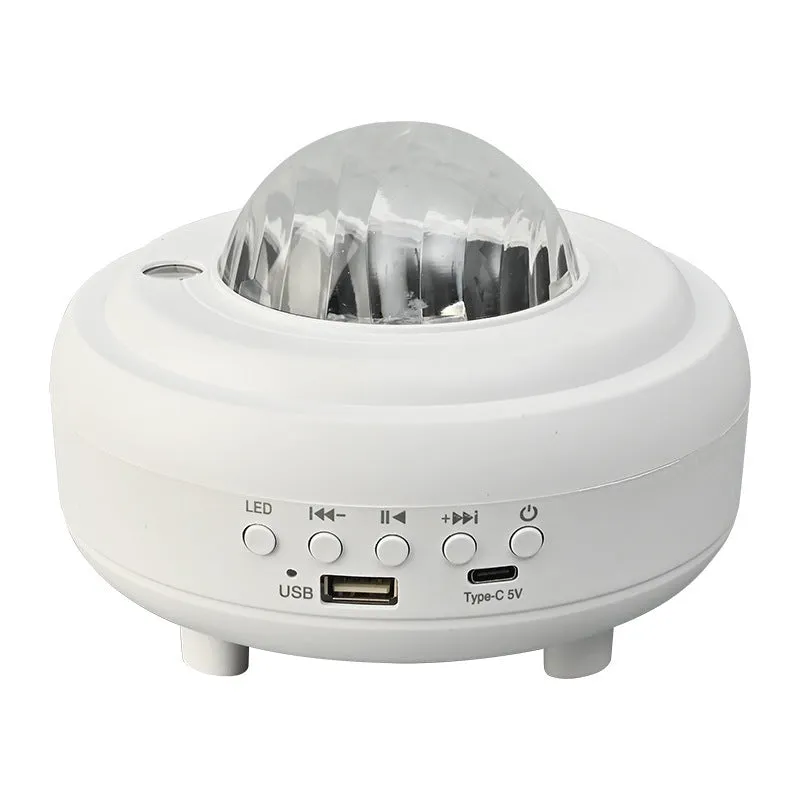 White Galaxy Star Projector Night Light on a table projecting blue starry sky onto a ceiling.
