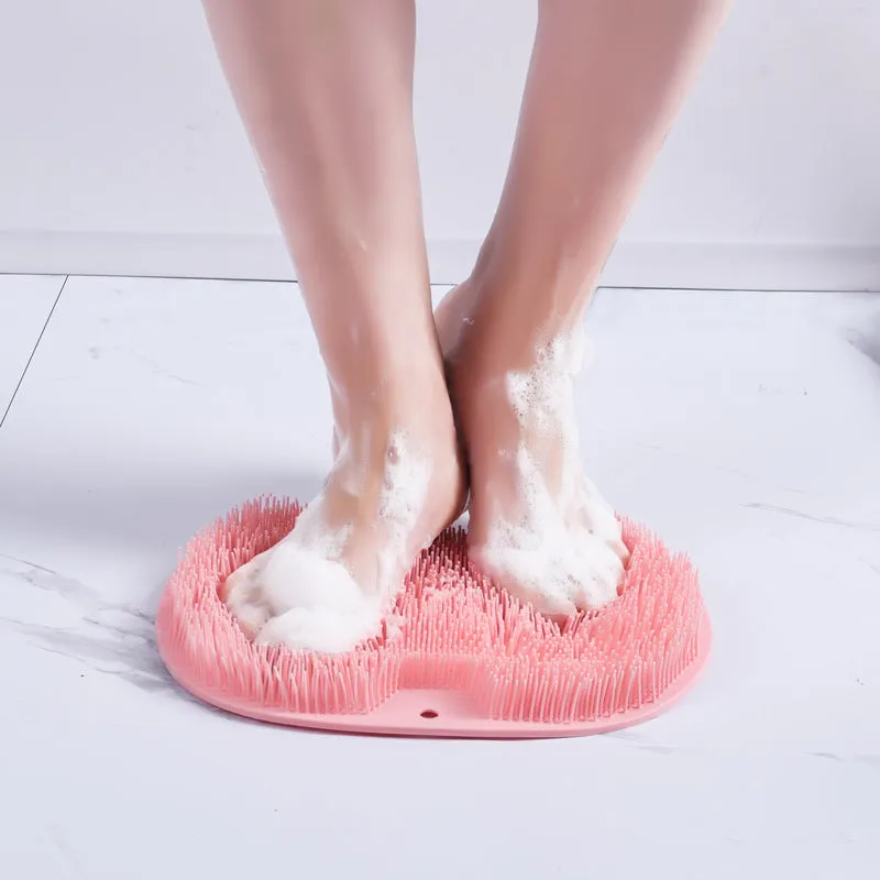 Orange non-slip massage bath brush with suction cups and soft silicone bristles on a bathroom floor.