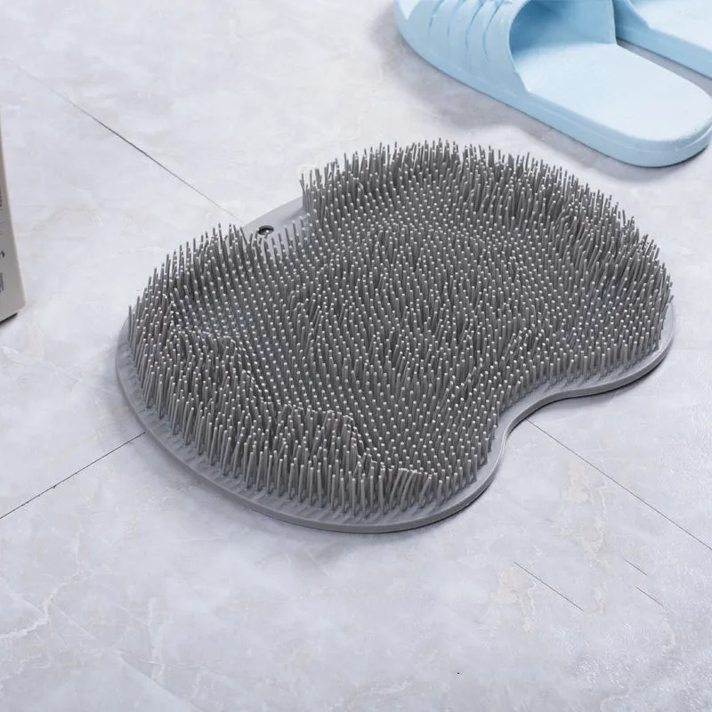 Orange non-slip massage bath brush with suction cups and soft silicone bristles on a bathroom floor.