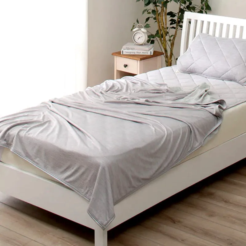 Blue and grey polyester cooling blanket with Japanese Q-Max fibres on a bed.