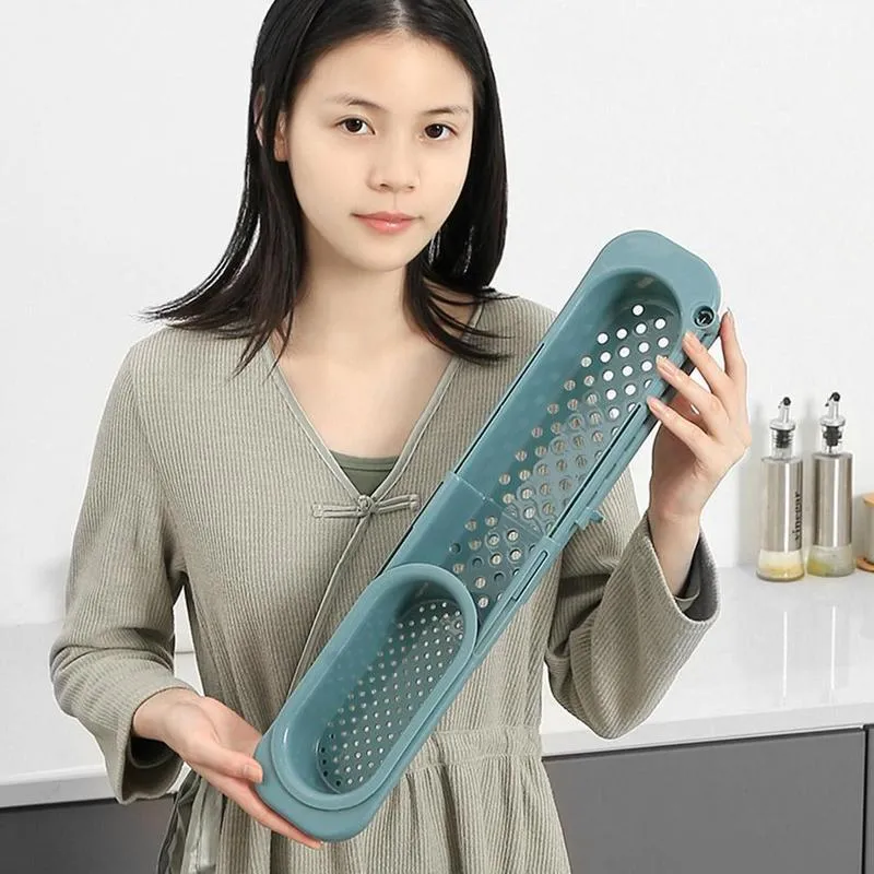 Blue grey telescopic sink rack holding a sponge and soap bar next to a kitchen tap
